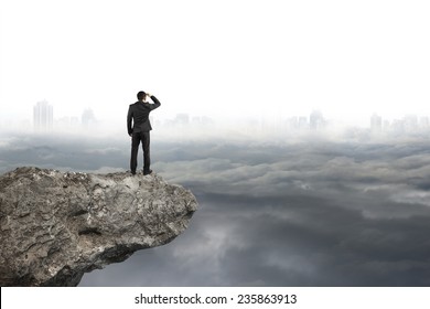 businessman looking on cliff with gray cloudy sky cityscape background - Powered by Shutterstock