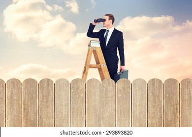 Businessman looking on a ladder against purple sky over fence