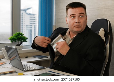 Businessman looking scared while taking a hip flask out of his jacket at work, hiding alcohol addiction issues of alcoholism in the workplace. The man hides a flask of rum in his jacket pocket.
