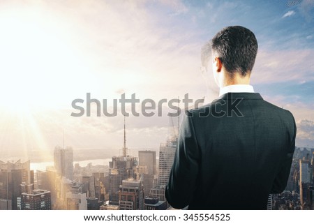 Businessman looking at sunrise from the top of building 