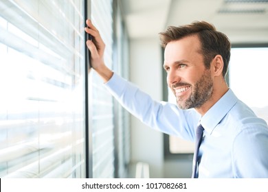 Businessman looking though the window at modern office - Powered by Shutterstock