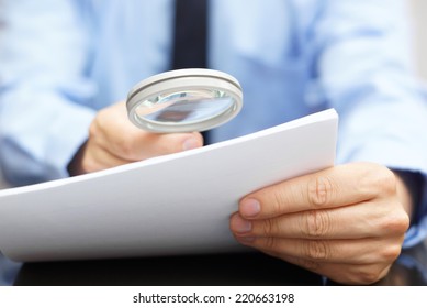 Businessman looking through a magnifying glass to contract
