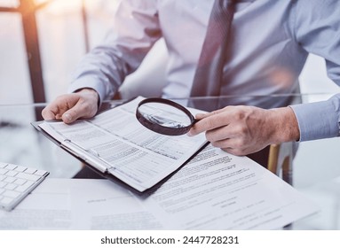 Businessman looking through a magnifying glass to documents - Powered by Shutterstock