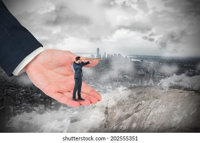 Businessman looking through telescope in large hand against large rock overlooking foggy city - Powered by Shutterstock