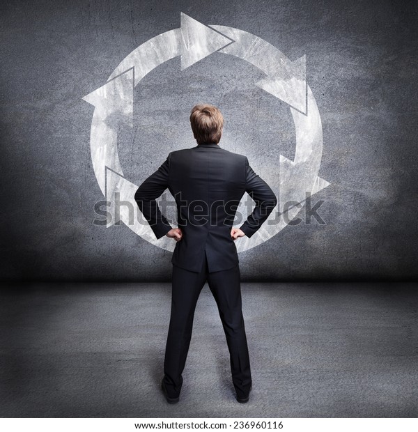 businessman looking at\
a wall with a loop\
sign