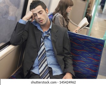 Businessman with loosened tie sleeping in commuter train - Powered by Shutterstock