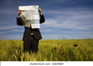 Businessman Lost In Field Using A Map