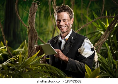 Businessman Lost In Jungle Holding A Digital Tablet And Smiling At Camera