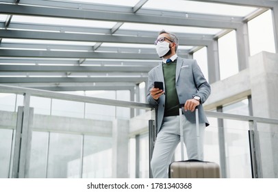 Businessman with luggage going on business trip, wearing face mask at the airport. - Powered by Shutterstock