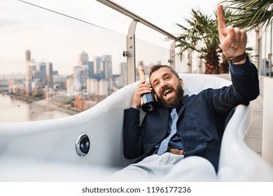 Businessman Lying In Empty Hot Tub, London View Panorama In The Background.