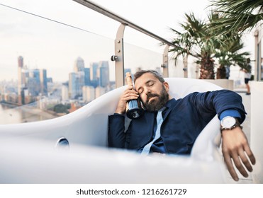 Businessman Lying In Empty Hot Tub, London View Panorama In The Background.