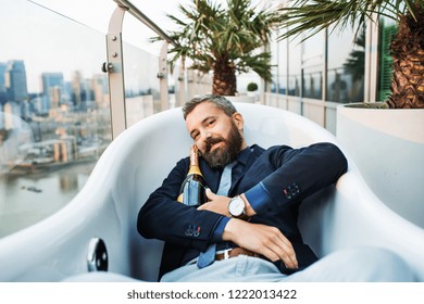 Businessman Lying In Empty Hot Tub, London View Panorama In The Background.