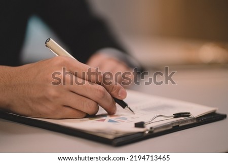 Businessman making agreement at office. it's a contract paper. Human hand holding pen mystery document on the table. It's a big decisions for business corporate. Stock photo © 