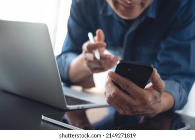 Businessman Making Face Time Video Calling, Using Zoom Online Meeting App Via Mobile App On Smart Phone With Laptop Computer And Digital Tablet On Office Table, Working At Home, Telecommuting Concept