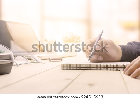 Businessman making notes at the office meeting with computer laptop and glasses.