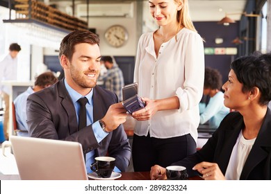 Businessman Making Payment By Phone In A Cafe