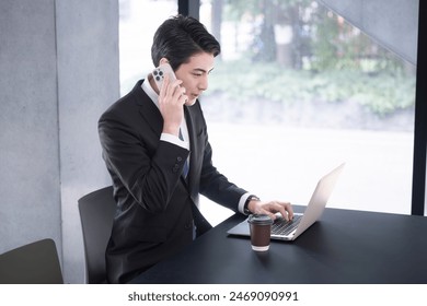 Businessman making a phone call while looking at a computer Image of a sales appointment or inquiry - Powered by Shutterstock