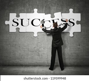 Businessman making a puzzle on the wall with the word Success