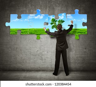 Businessman making a puzzle on the wall with  picture of nature