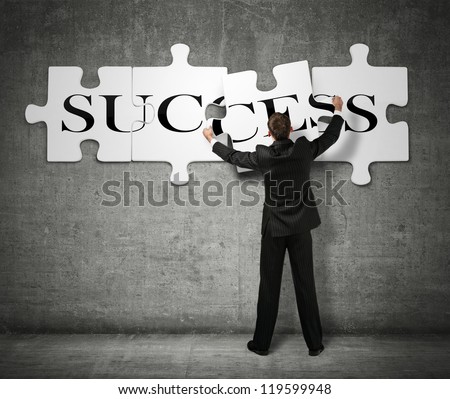 Businessman making a puzzle on the wall with the word Success