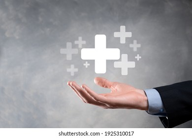 Businessman, man hold in hand offer positive thing such as profit, benefits, development, CSR represented by plus sign.The hand shows the plus sign. - Shutterstock ID 1925310017
