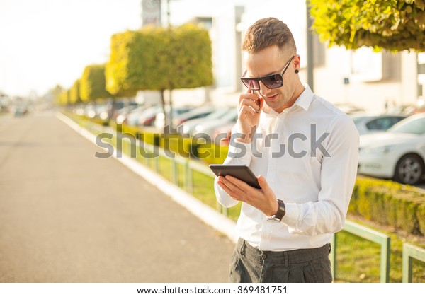 Businessman Man With Mobile Phone and Tablet\
computer in hands, In City, Urban\
Space