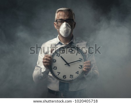 Businessman with mask holding a clock and polluted air, doomsday warning concept