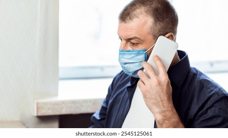 Businessman In Medical Mask Talking On Phone Working On Laptop Computer At Home During Pandemic Outbreak Quarantine. - Powered by Shutterstock