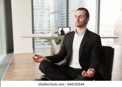 Businessman meditates in lotus position on coach in modern office. Company leader practicing yoga during break at work for strength recovery and stress relief. Man relaxing near workplace with laptop - Powered by Shutterstock