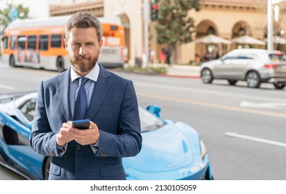 Businessman Messaging On Phone Next To Luxury Car