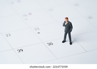 Businessman miniature figure standing on number date 30 on calendar for getting money of pay day of salary concept.