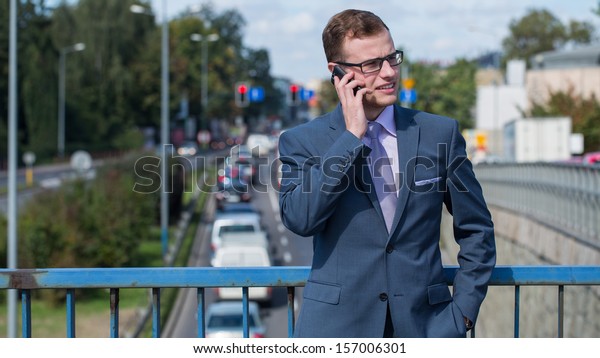 Businessman with mobile phone. In the background\
bustling street.