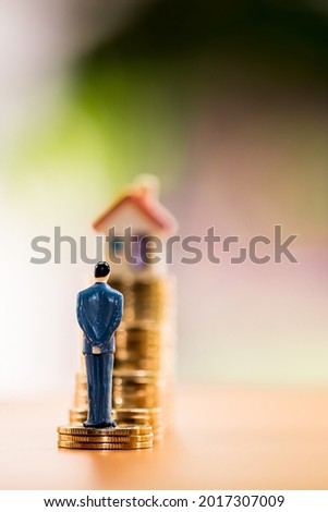 Businessman model standing on stack gold coin with grow value with working capital management and home model is destination in the garden, Loan and business investment for real estate concept.