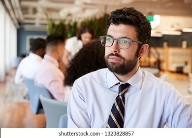 Businessman In Modern Office With Colleagues Meeting Around Table In Background