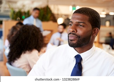 Businessman In Modern Office With Colleagues Meeting Around Table In Background