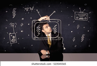 A Businessman In Modern Stylish Elegant Suit Standing On A Small Ladder And Drawing Pie And Block Charts On Grey Wall Background With Exponential Progressing Curves, Lines, Circles, Angles, Numbers