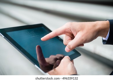 Businessman Navigating On A Tablet Computer Using His Finger On The Touchscreen As He Surfs The Internet, Close Up View