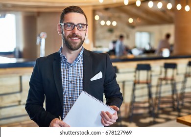 Businessman with notepad looking at camera in restaurant