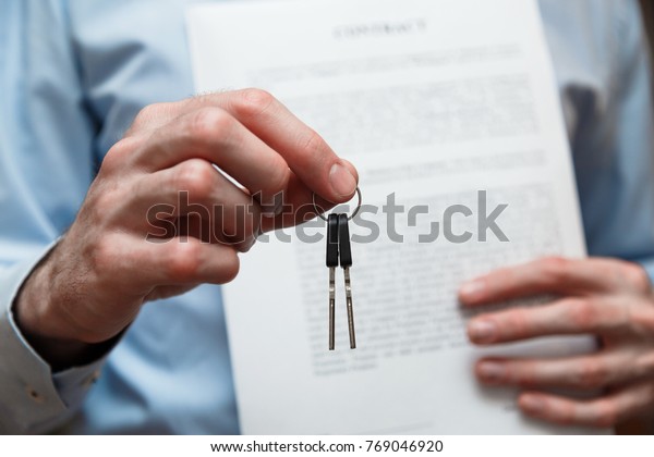 Businessman offering a key with contract.\
Rental agreement with\
contract.
