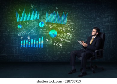 Businessman In Office Chair With Tablet In Hand And High Tech Graph Charts Concept On Background