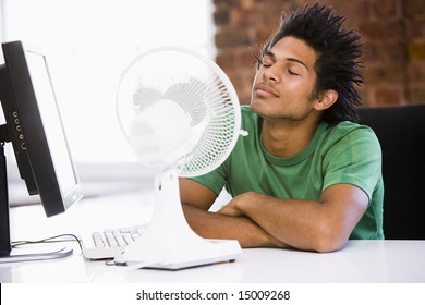 Businessman In Office With Computer And Fan Cooling Off