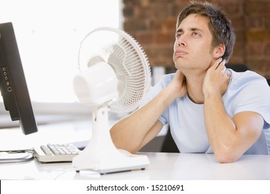 Businessman in office with computer and fan cooling off - Powered by Shutterstock