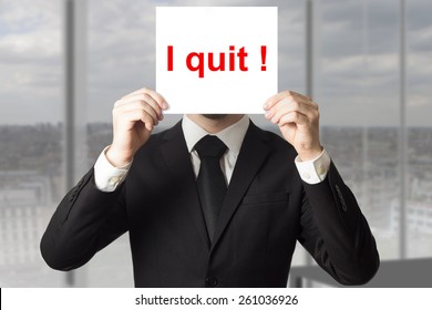businessman in office hiding face behind sign i quit