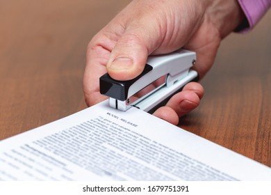 Businessman in office stapler fastens documents, paper sheets