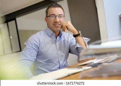 Businessman in office working on desktop computer, thoughtful look