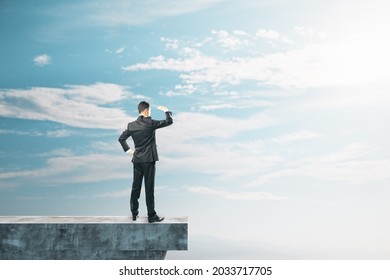 Businessman On Abstract Concrete Edge Looking Into The Distance On Creative Bright Sky Background With Mock Up Place. Future, Tomorrow And Success Concept