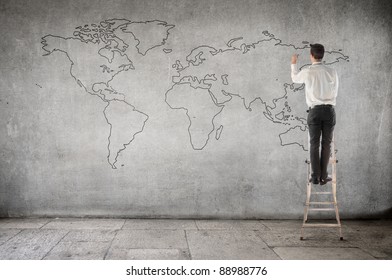 Businessman On A Ladder Drawing A World Map