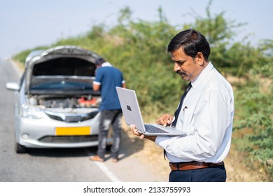 Businessman On Roadside Busy Working On Laptop In Front Of Broken Car While Mechanic Buy Reparing Car - Concept Of Mobile Car Service, Busy Work Schedule And Misfortune