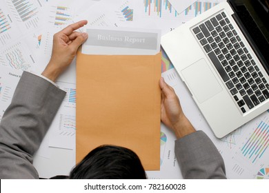 Businessman Open Brown Envelope For Analysis Report Paper And Researching New Product Strategy For Lunch Next Quarter On Desk With Laptop In Office, Business Executive Going Through Paperwork Concept.