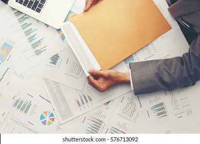 Businessman Open Brown Envelope For Evaluating Business Report, Examining Report Papers On Table In Desk Office.